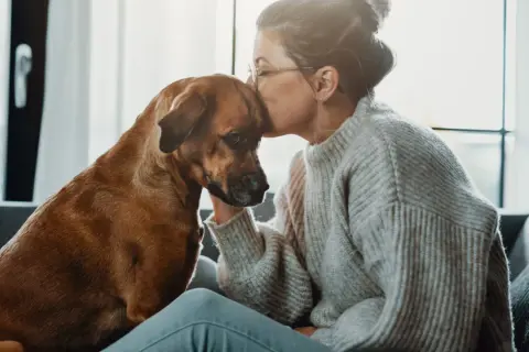 Mujer besa la frente de su perro, un momento tierno que demuestra que se puede sacrificar un perro por amor.